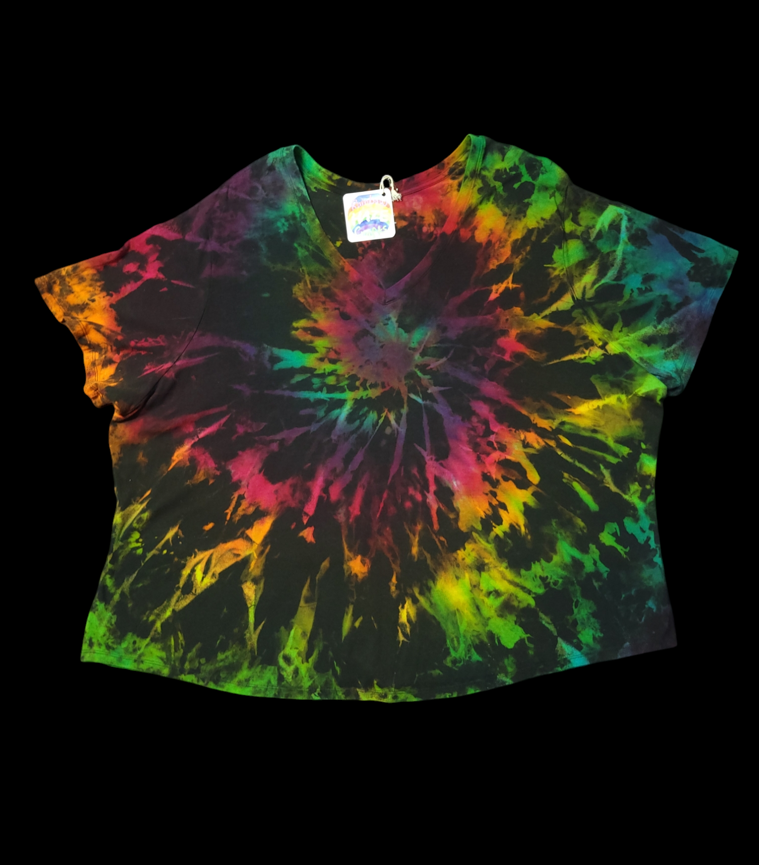 Front view of short-sleeved t-shirt with brilliant rainbow colors splashing out from its center on a dark background.