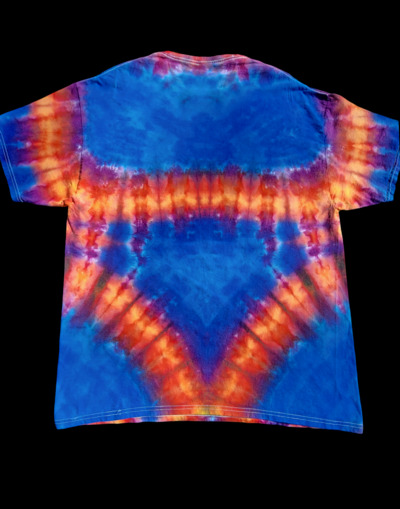 Back view of XL tie-dye t-shirt in bright oranges and pinks on a blue background. Interesting yoke-like pattern flows around the sleeves and back, creating a central triangle of blue.